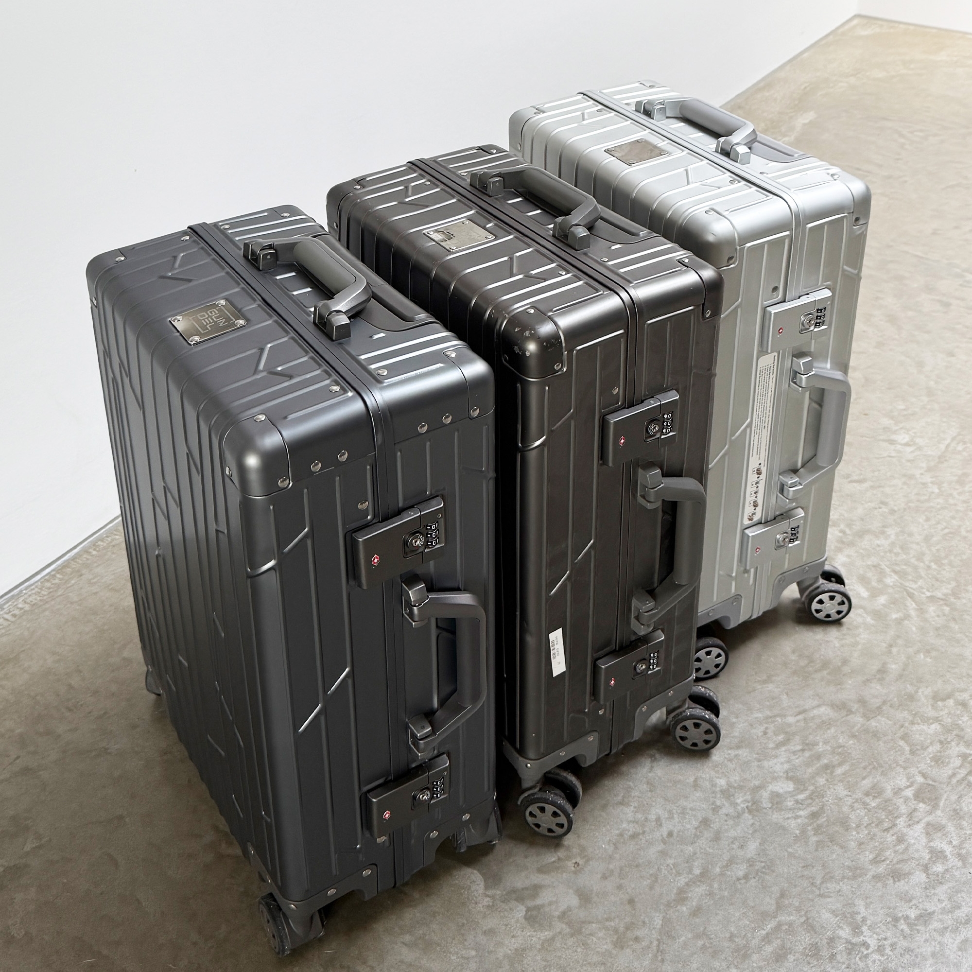 Two space grey GUNDEL suitcases with a line pattern standing in a field with dry grass.